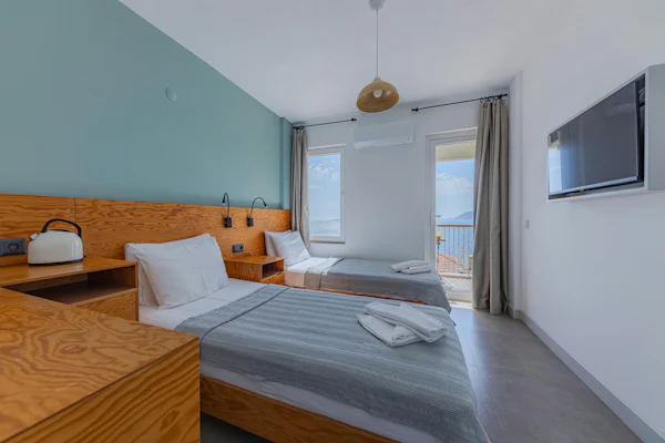 Two twin beds in a bright room with a view of the sea