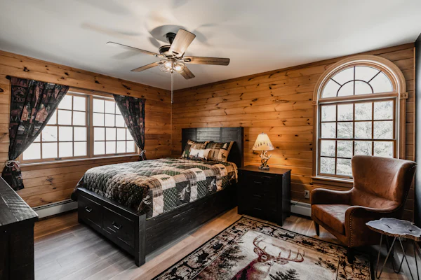 Bedroom with a queen bed, an armchair, and an arched window