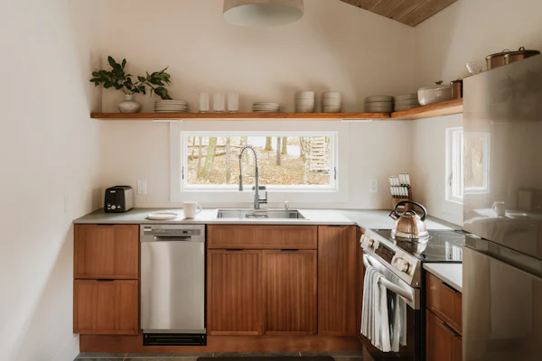 Kitchen with warm wood cabinets, stainless appliances, and a window to the trees